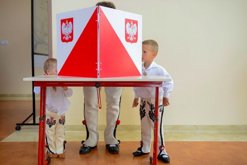 A man in traditional clothes is watched by his young boys as he sits in the voting booth on July 12, 2020 in Zab near Zakopane, during the second round of Poland's presidential election.. (Photo by Bartosz Siedlik/AFP Photo)
